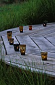 DESIGNER CLARE MATTHEWS: THE DECK CHAIR AT DUSK WITH CANDLES  SURROUNDED BY STIPA ARUNDINACEA