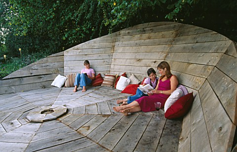 DESIGNER_CLARE_MATTHEWS_CLARE_MATTHEWS__HARRIET_AND_NANCY_RELAX__IN_THE_DECK_CHAIR_AT_DUSK_WITH_CAND