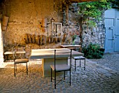 LA CHABAUDE  FRANCE. DESIGNER - PHILIPPE COTTET: A PLACE TO SIT: COBBLED TERRACE WITH TABLE AND CHAIRS