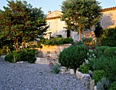 LA CHABAUDE  FRANCE. DESIGNER - PHILIPPE COTTET: GRAVEL TERRACE AND STONE WATER FEATURE BY THE HOUSE
