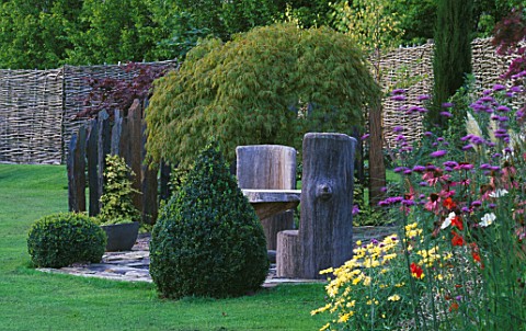 WOODEN_SEATS_AND_TABLE_ON_SLATE_TERRACE_WITH_BOX_TOPIARY_SHAPES_AND_ACER_PALMATUM_DISSECTUM__DESIGNE