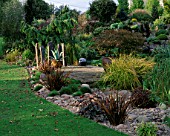 VIEW ACROSS WOODEN PONTOON WITH STANDING STONES  AGAVE IN CONTAINER AND GRAVEL BORDER. DESIGNER : JOHN MASSEY