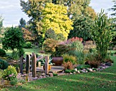 BORDER WITH WOODEN PONTOON  STANDING STONES  GRAVEL  PEBBLES AND AGAVE IN CONTAINER. DESIGNER : JOHN MASSEY
