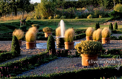 PARSONAGE__OMBERSLEY__WORCESTERSHIRE_PARTERRE_ON_OLD_TENNIS_COURT_WITH_TERRACOTTA_CONTAINERS_PLANTED