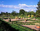 PARSONAGE  OMBERSLEY  WORCESTERSHIRE: PARTERRE ON OLD TENNIS COURT WITH TERRACOTTA CONTAINERS PLANTED WITH STIPA TENUISSIMA AROUND A WATER SPOUT