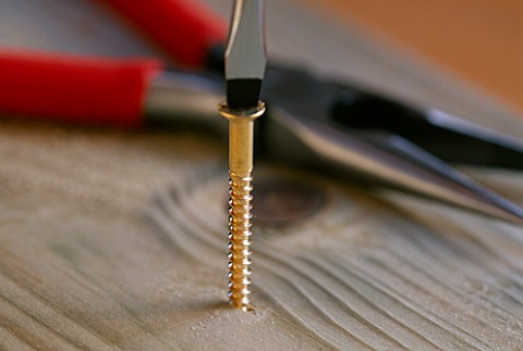 SCREW_DRIVER_DRIVING_BRASS_SCREW_INTO_WOOD