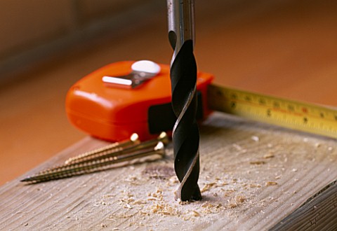DRILLING_INTO_WOOD_WITH_TAPE_MEASURE_AND_BRASS_SCREWS