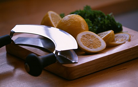 SLICING_LEMONS_WITH_CURVED_KNIFE__PARSLEY_IN_BACKGROUND