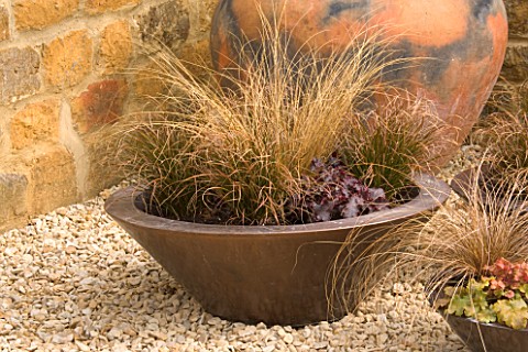 DESIGNER_CLIVE_NICHOLS_COPPER_CONTAINER_IN_GRAVEL_COURTYARD_PLANTED_WITH_HEUCHERA_X_BRIZOIDES_CAN_CA