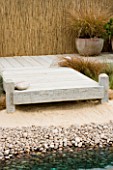 TERRACOTTA CONTAINER ON DECKING IN SEASIDE GARDEN PLANTED WITH GRASSES: DESIGNERS NIGEL DUFF AND GREG RIDDLE. BEACH  BOARDWALK