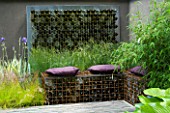 STEEL CAGE SEAT MADE FROM GABIONS FILLED WITH BOTTLES  PURPLE CUSHIONS AND BOTTLE WALL FEATURE. DESIGN BY SCENIC BLUE. CHELSEA 2005