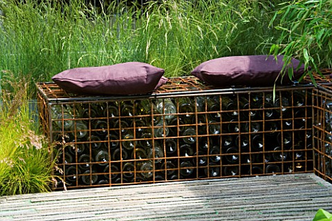 STEEL_CAGE_SEAT_MADE_FROM_GABIONS_FILLED_WITH_BOTTLES_ON_SEAT_ARE_PURPLE_CUSHIONS_DESIGN_BY_SCENIC_B