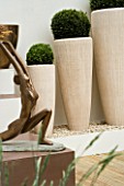 BRONZE STATUE IN FRONT OF THREE STONE RESIN CONTAINERS PLANTED WITH BOX BALLS. DESIGN BY GREEN INTERIORS