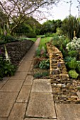 PATH LEADING AWAY FROM THE PATIO TO THE LAWN  WITH A DRYSTONE WALL ON THE RIGHT. WINGWELL NURSERY   RUTLAND