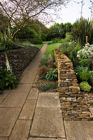 PATH_LEADING_AWAY_FROM_THE_PATIO_TO_THE_LAWN__WITH_A_DRYSTONE_WALL_ON_THE_RIGHT_WINGWELL_NURSERY___R
