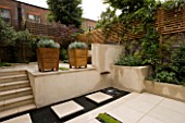VIEW ACROSS CONTEMPORARY CLASSIC GARDEN WITH COPPER WATER FEATURE  STEPPING STONES  STEPS AND PORTUGUESE LIMESTONE PAVING.  DESIGNER CHARLOTTE ROWE