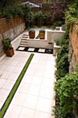 VIEW ACROSS CONTEMPORARY CLASSIC GARDEN WITH PLANTED RILL  COPPER WATER FEATURE  PORTUGUESE LIMESTONE PAVING AND STEPS .  DESIGNER: CHARLOTTE ROWE