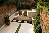 VIEW ACROSS CONTEMPORARY CLASSIC GARDEN WITH PLANTED RILL  COPPER WATER FEATURE  PORTUGUESE LIMESTONE PAVING  AND STEPS .  DESIGNER: CHARLOTTE ROWE
