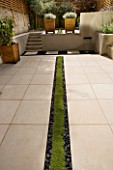 PLANTED RILL EDGED WITH POLISHED BLACK PEBBLES RUNS THROUGH MIDDLE OF CONTEMPORARY GARDEN DESIGNED BY CHARLOTTE ROWE
