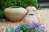 FOUR TERRACOTTA CONTAINERS ON A GRAVEL PATH BESIDE THE HOUSE. CLARE MATTHEWS GARDEN  DEVON