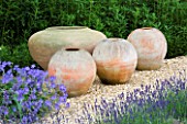FOUR TERRACOTTA CONTAINERS ON A GRAVEL PATH BESIDE THE HOUSE. CLARE MATTHEWS GARDEN  DEVON