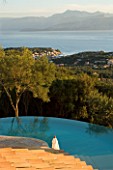VIEW OF THE ALBANIAN MOUNTAINS FROM THE TERRACE WITH AN OLIVE TREE AND INFINITY SWIMMING POOL IN THE FOREGROUND: GINA PRICES GARDEN  CORFU