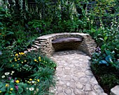 CHELSEA FLOWER SHOW 2005. PAUSE FOR THOUGHT COURTYARD GARDEN  DESIGNERS: LIZ ROBINSON AND PHIL KAYE: DRY STONE WALL WITH RECLAIMED TIMBER SEAT WITH SHADE-LOVING PLANTS