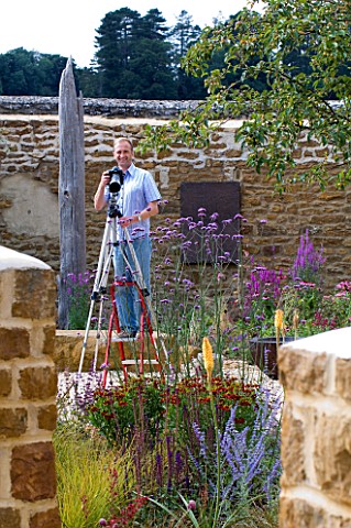 CLIVE_NICHOLS_ON_A_STEP_LADDER_IN_HIS_GARDEN_WITH_CAMERAS