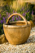 RICKYARD BARN GARDEN  NORTHAMPTONSHIRE: OLD CHINESE WICKER BASKET BESIDE A BORDER WITH SALVIAS AND STIPA ARUNDINACEA IN THE GRAVEL GARDEN