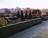 VIEW ACROSS PARTERRE TO OPEN COUNTRYSIDE AT PETTIFERS IN  FROST.  TOPIARY