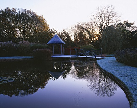 GARDEN_DESIGNED_BY_DUNCAN_HEATHER_THE_SUMMERHOUSE_AND_WOODEN_BRIDGE_ACROSS_THE_POOL_IN_WINTER_WITH_C