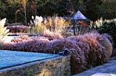 GARDEN DESIGNED BY DUNCAN HEATHER: STONE WALL  BOY SCULPTURE  CONTAINER  PAMPAS GRASS  STIP GIGANTEA AND THE SUMMERHOUSE IN FROST. WINTER