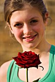 GIRL (AGED 13) HOLDING A RED ROSE AND SMILING