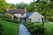 DESIGNER HELEN DOOLEY - ROSE COTTAGE  DORSET: VIEW OF COTTAGE FROM FRONT GATE. SLATE PATH  ASTRANTIA ROMA  EUPHORBIA POLYCHROMA THALICTRUM ELIN