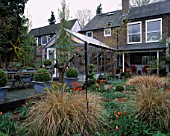 LISETTE PLEASANCE GARDEN  LONDON: VIEW TO THE HOUSE WITH CONSERVATORY  GRAVEL  BOX TOPIARY  STIPA ARUNDINACEA AND BALLERINA TULIPS