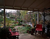LISETTE PLEASANCE GARDEN  LONDON: VIEW FROM VERANDAH WITH PINK DECKCHAIRS ACROSS GRAVEL GARDEN WITH BOX TOPIARY  STIPA ARUNDINACEA  DECKED TERRACE AND TULIPS