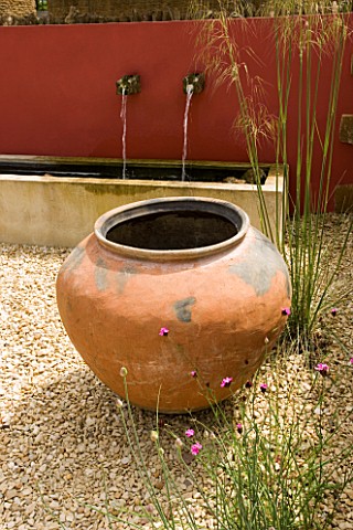 RICKYARD_BARN__NORTHAMPTONSHIRE_THE_GRAVEL_COURTYARD_IN_JUNE_WITH_LARGE_TERRACOTTA_CONTAINER__RED_WA