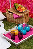 DESIGNER CLARE MATTHEWS: WIND BREAK SCREEN PROJECT -TRAY WITH GLASSES  ORANGE JUICE AND BLUE CANDLES  HAMPER AND METAL FRUIT BOWL WITH PEACHES AND MANGOES