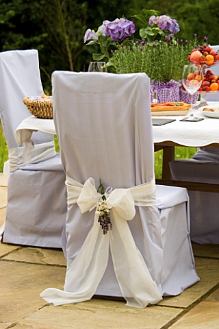 DESIGNER_CLARE_MATTHEWS_CHAIR_COVERED_WITH_PALE_BLUE_SHEET_WITH_WHITE_RIBBON_AND_BOUQUET_OF_LAVENDER