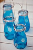 DESIGNER: CLARE MATTHEWS -  LANTERN STAND - BLUE PAINTED GLASS JARS WITH WIRE HANDLES