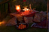 DESIGNER: CLARE MATTHEWS - SARI CANOPY PROJECT: INSIDE THE CANOPY IN THE EVENING WITH LIGHTING.  LOW SLEEPER TABLE  ORANGES IN BOWL  CUSHIONS  GLASS BOWL WITH CHERRIES  CANDLES