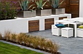 MINIMALIST GARDEN DESIGNED BY WYNNIATT-HUSEY CLARKE: GREY SLATE PATIO WITH THREE AGAVES IN METAL CONTAINERS  WHITE WALL  STIPA ARUNDINACEA AND WHITE TABLE