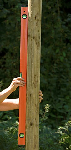 DESIGNER_CLARE_MATTHEWS__TREEHOUSE_PROJECT_USING_SPIRIT_LEVEL_TO_CHECK_ON_WOODEN_UPRIGHT