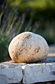 SPHERICAL ROCK SITS ON TOP OF STONE WALL IN GINA PRICES CORFU GARDEN.
