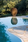 VIEW TOWARDS TERRACOTTA URN REFLECTED IN SWIMMING POOL IN GINA PRICES CORFU GARDEN.