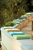 GREEN AND BLUE CUSHIONS SIT ON TOP OF LOW LEVEL WALL IN  GINA PRICES CORFU GARDEN.
