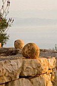 SPHERICAL STONES ON TOP OF DRY STONE WALL IN GINA PRICES CORFU GARDEN.