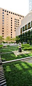 MARUNOUCHI HOTEL  TOKYO  JAPAN. MODERN FORMAL ROOF GARDEN WITH OFFICE BLOCKS - POLISHED GRANITE SCULPTURES ON STONE PEDESTALS WITH GREEN CARPET   DECKING AND TREES