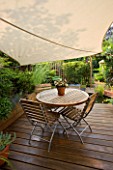 WOODEN DECKING WITH WOODEN TABLE AND CHAIRS  SHADE CANOPY  CANVAS. KATHY TAYLORS SMALL TOWN GARDEN  LONDON