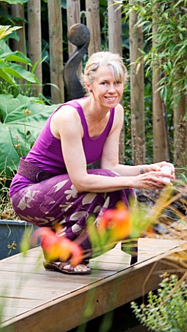 KATHY_TAYLOR_BESIDE_POND_IN_DECKED_AREA_IN_HER_LONDON_GARDEN